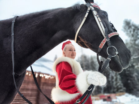 Beautiful girl in national dress posing with a horse during holiday celebrationの写真素材