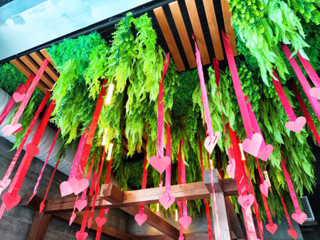 Brightly colored greenery and paper hearts hang from the ceiling, adding a festive and lively touch to the indoor environment.の写真素材