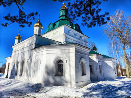 A beautiful church stands out against the white snow with its golden domes shining bright under the blue sky during winter.の写真素材