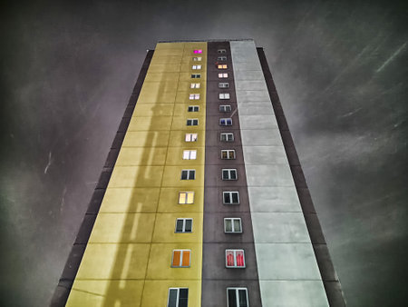 A tall residential building stands prominently against a stormy sky, showcasing multiple colorful...
