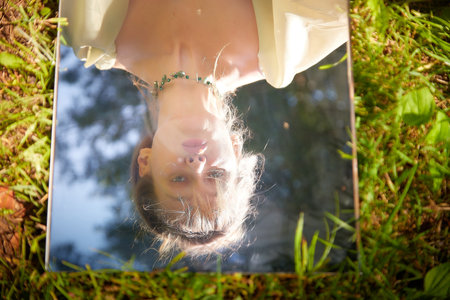A fairy princess in a beautiful dress, laying on the forest floor, reflected in a mirror....
