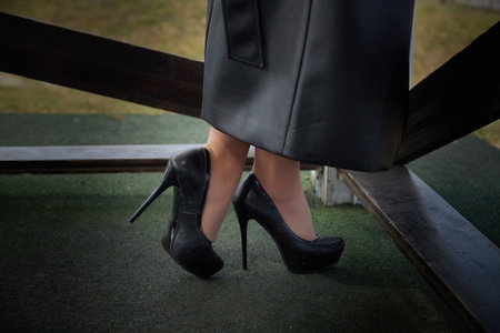 A woman in black high heels stands on a green surface, showing elegance against a natural backdrop.の写真素材