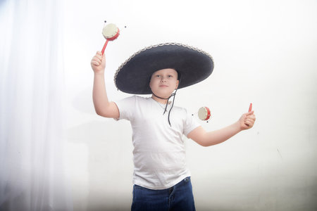 Child wearing a large sombrero and holding maracas while having fun celebrating a cultural eventの写真素材