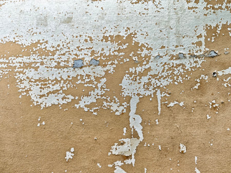 Old wall displays layers of peeling paint, showing a textured surface, highlighting the effects of...