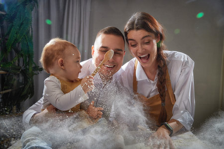 A family enjoys a fun cooking session, playfully covered in flour while engaging with their little...
