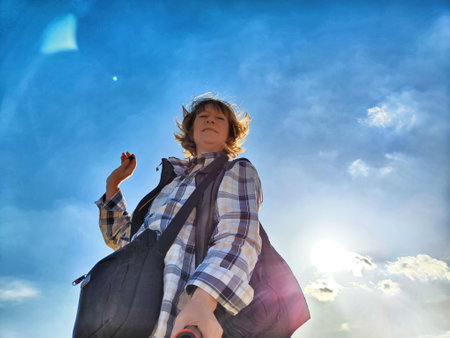 Blonde woman captures a selfie while exploring outdoors, enjoying her travel adventure under a sunny sky.の写真素材