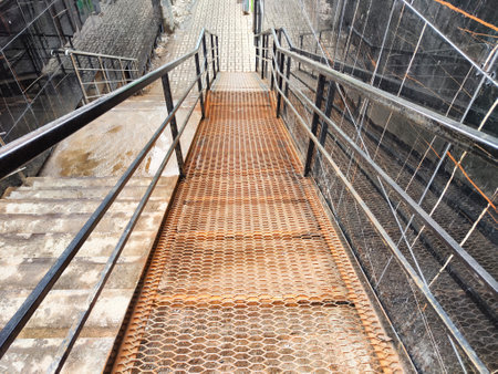 Stairway made of metal grating leads downwards at a construction site, surrounded by scaffolding and...