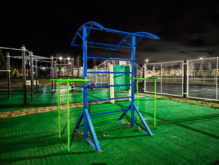 A colorful set of outdoor workout bars sits in a dark park, illuminated by soft lighting, inviting night-time exercise.の写真素材