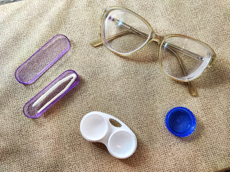 Eyewear and contact lens items are neatly placed on a textured fabric, showcasing tools for maintaining visual clarity and comfort.の写真素材