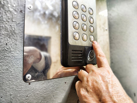A hand is seen pressing the buttons on a keypad mounted on a wall, indicating access to a secure...