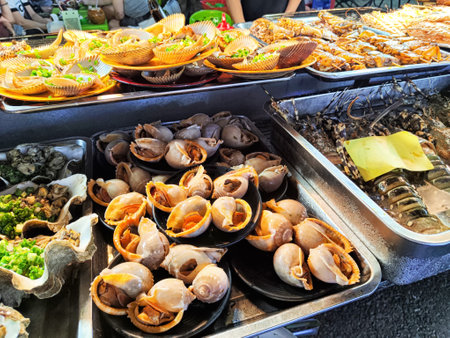 Fresh seafood, including shellfish and grilled items, is served at a lively market stall, attracting food lovers and vendors alike.の写真素材