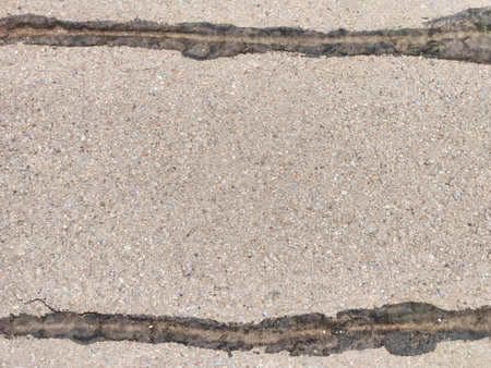 Two distinct cracks run through the smooth concrete, showing the texture and weathering of the surface in an urban environment.の写真素材