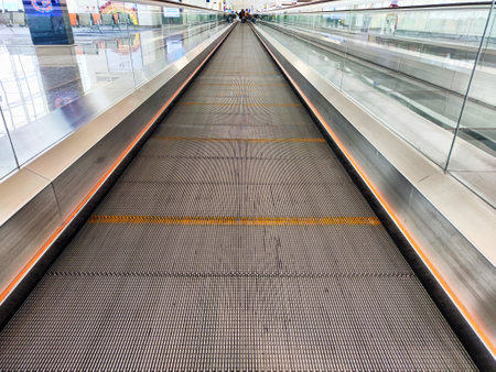 Travelers use a moving walkway to reach various gates in a busy airport terminal, showing modern architecture and efficient design.の写真素材