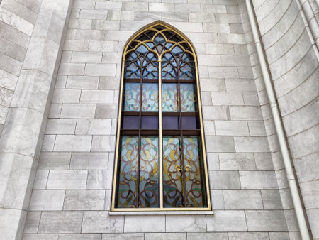 Sunlight illuminates the colorful stained glass window of a historic building, highlighting its detailed patterns and architecture.の写真素材