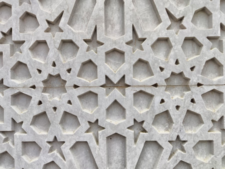 Detailed close-up of a textured concrete wall featuring star and polygon shapes in a modern architectural setting.の写真素材