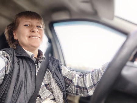 This middle-aged woman takes a cheerful selfie while driving, showing her excitement for the upcoming adventures on her road trip.の写真素材