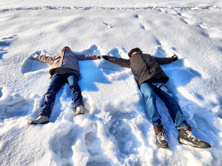 Enjoying winter by making snow angels in the bright sunlight on a snowy landscape during the afternoonの写真素材