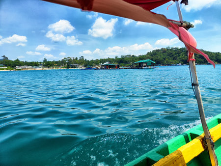 Bright turquoise waters stretch out under fluffy clouds as a boat glides peacefully, surrounded by...