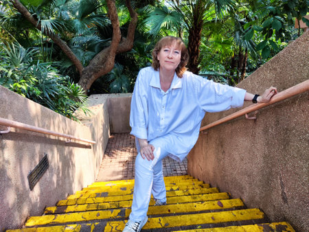 Blonde woman poses confidently on vibrant yellow stairs amid lush greenery during a travel adventure...