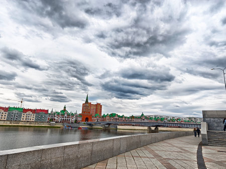 Visitors stroll along embankment in Yoshkar-Ola, enjoying the colorful architecture and moody sky above the river.の写真素材