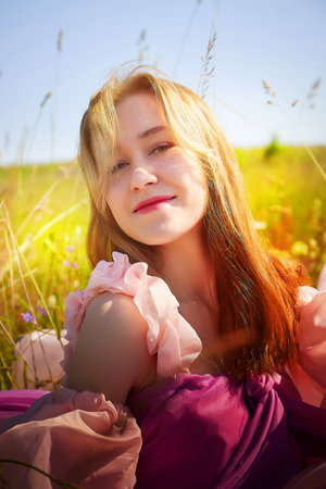 Young woman enjoying a sunny day in a vibrant flower field with a joyful expression caught on cameraの写真素材