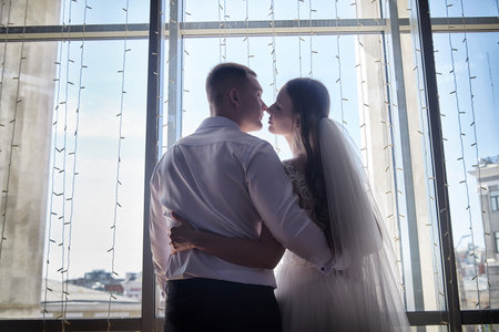 Couple enjoys a romantic moment during wedding registration with beautiful window backdropの写真素材