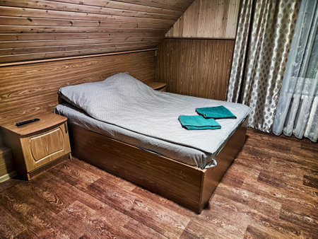 A simple, inviting bedroom features a neatly made bed, wooden walls, and a calming atmosphere perfect for relaxation.の写真素材