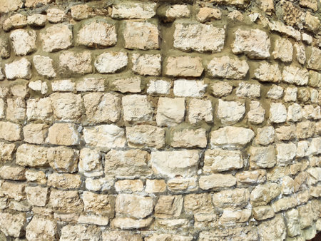 A textured stone wall features varied sizes and shapes, offering a rustic backdrop perfect for design projects and creative ideas.の写真素材