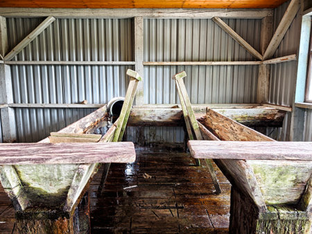 Wooden benches in a rustic barn display weathered textures and a tranquil ambiance, surrounded by a minimalistic interior space.の写真素材