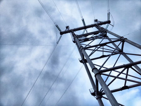 Power lines stretch high above the Krasnoyarsk Hydroelectric Power Station under a cloudy sky,...