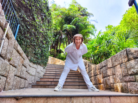 Blonde woman takes a lively selfie on an outdoor staircase, capturing her excitement during the travel excursion in a beautiful green setting.の写真素材