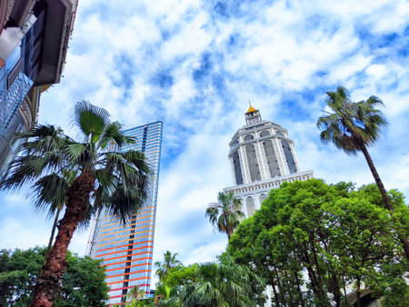 Palm trees frame a historic building against a backdrop of modern skyscrapers and a dynamic sky filled with clouds.の写真素材
