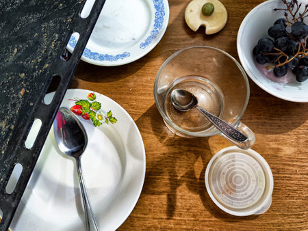 Various dirty dishes and utensils are scattered across a wooden table.の写真素材