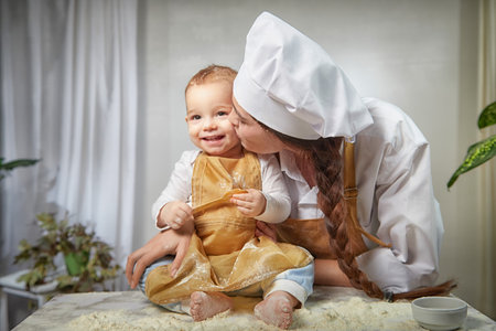 A family enjoys a fun cooking session, playfully covered in flour while engaging with their little ones in a warm kitchen. Mother and son having funの写真素材