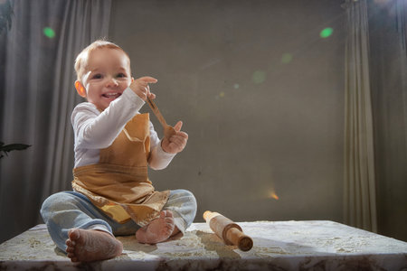 A young boy joyfully plays with flour during a creative cooking-themed photo shoot in a studio...
