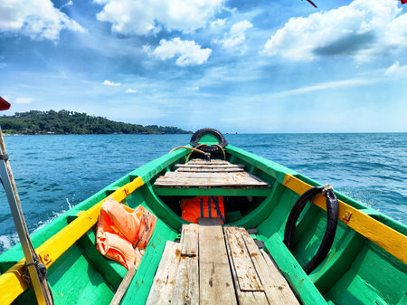 A vibrant boat floats on turquoise water, surrounded by a lush tropical landscape under a sunny sky...