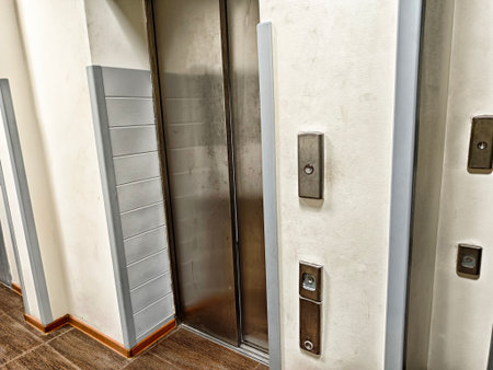 A modern elevator entrance features sleek buttons and metallic panels in a minimalist corporate building interior.の写真素材