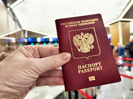 A hand holds a Russian passport in line at customs, signaling preparation for departure on an international trip.の写真素材