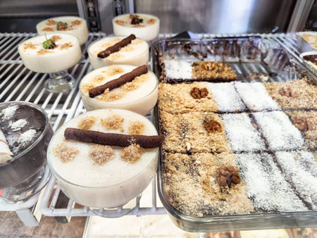 A variety of desserts are arranged neatly in a bakery display, showcasing creamy puddings alongside sweet chocolate treats, inviting customers.の写真素材