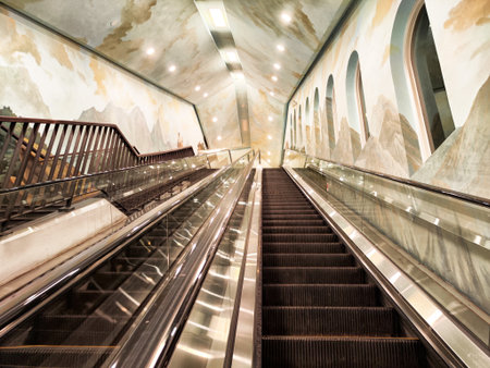 Travelers move up the sleek escalators in a contemporary subway station adorned with stunning murals depicting mountains and landscapes.の写真素材