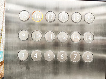 An elevator button panel features numbered buttons up to 20 with a distinct highlight on the 16th floor button, indicating active selection.の写真素材
