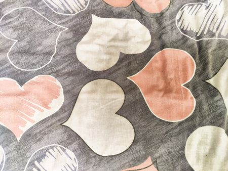 Vibrant heart shapes in soft pink, white, and gray adorn a fabric, adding a cheerful touch to home...