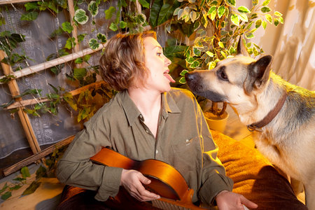 Loving moments between a musician and her dog in a cozy indoor setting filled with plantsの写真素材