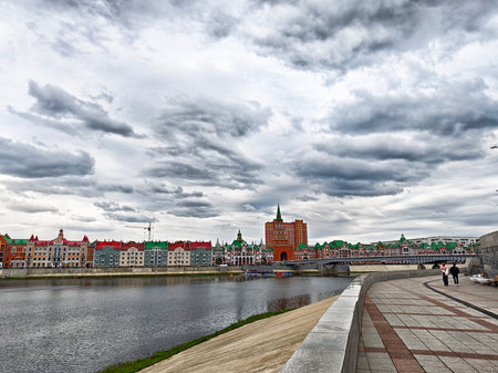 Visitors stroll along the embankment in Yoshkar-Ola, admiring the vibrant architecture under a dramatic sky.の写真素材