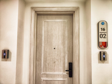 A light-colored hotel door stands prominently, showing an access panel and the room number,...