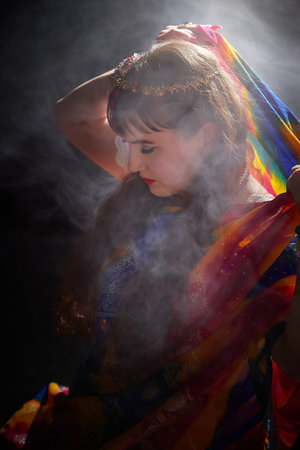 Blonde woman posing in a colorful sari during an Indian style photo shoot in a mystical setting