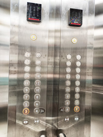 Two sleek elevator panels show floor buttons from ground to upper levels.