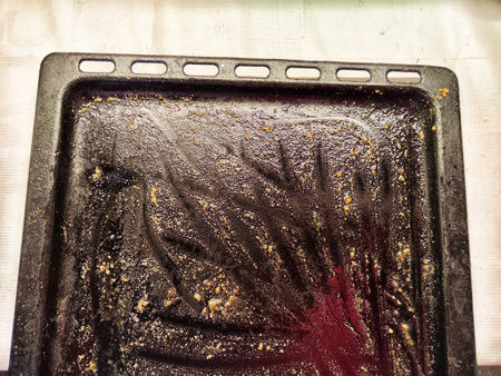 A cooking tray shows significant grease and food residue, indicating a recent meal preparation. The tray, with its dirty surface, represents the aftermath of cooking in a household kitchen.の写真素材