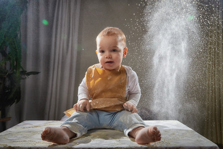 A young boy joyfully plays with flour during a creative cooking-themed photo shoot in a studio settingの写真素材