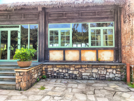 Charming restaurant features green-framed windows and a stone pathway, nestled among vibrant tropical plants under a clear sky.の写真素材